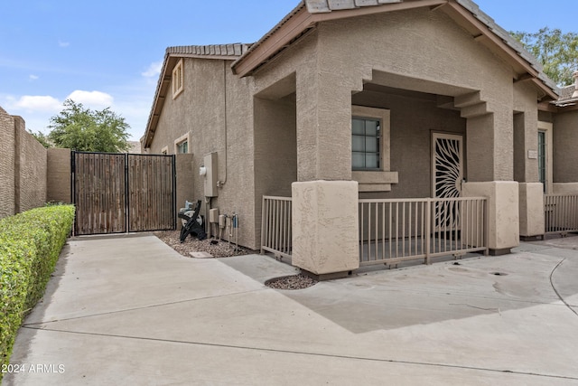view of side of home with stucco siding, fence, a gate, and a tile roof
