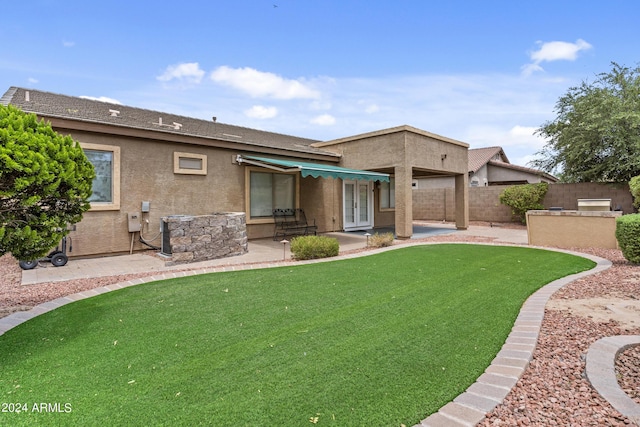 back of property with a patio, fence private yard, an outdoor kitchen, stucco siding, and french doors