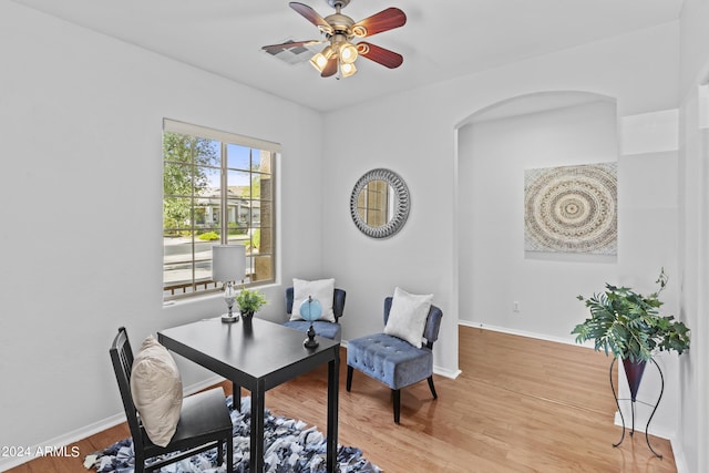 home office featuring baseboards, wood finished floors, a ceiling fan, and arched walkways
