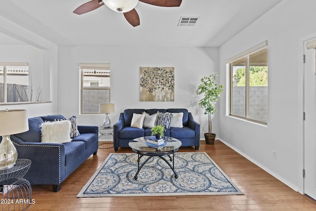 living area featuring wood finished floors, visible vents, a ceiling fan, and baseboards