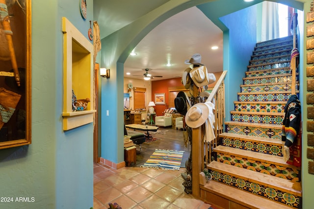 stairs featuring ceiling fan and tile patterned floors