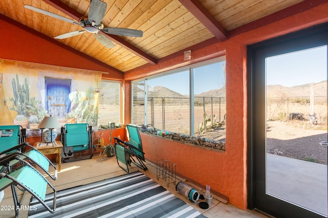 sunroom / solarium with a healthy amount of sunlight, a mountain view, and vaulted ceiling with beams