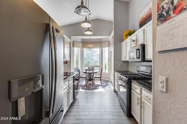 kitchen with white cabinetry, appliances with stainless steel finishes, decorative light fixtures, decorative backsplash, and vaulted ceiling