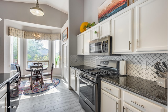 kitchen featuring vaulted ceiling, white cabinetry, decorative light fixtures, and appliances with stainless steel finishes