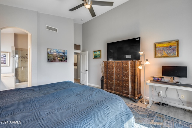 bedroom featuring ensuite bathroom, ceiling fan, a towering ceiling, and light hardwood / wood-style flooring