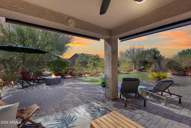 patio terrace at dusk featuring a lawn and a fire pit