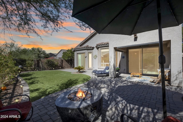 patio terrace at dusk with a lawn and a fire pit