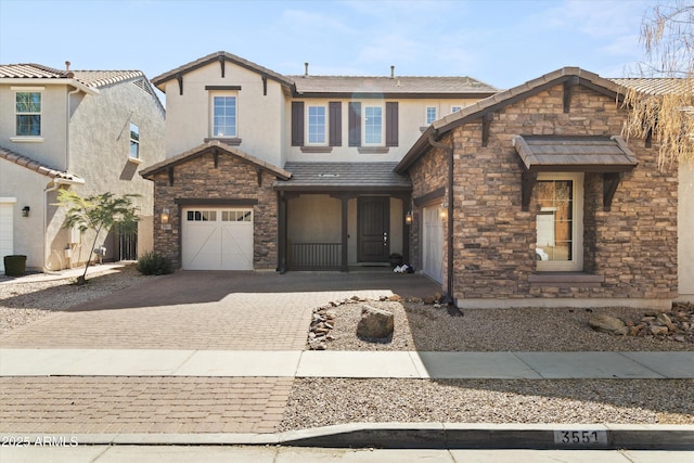 view of front facade featuring stone siding, decorative driveway, a garage, and stucco siding