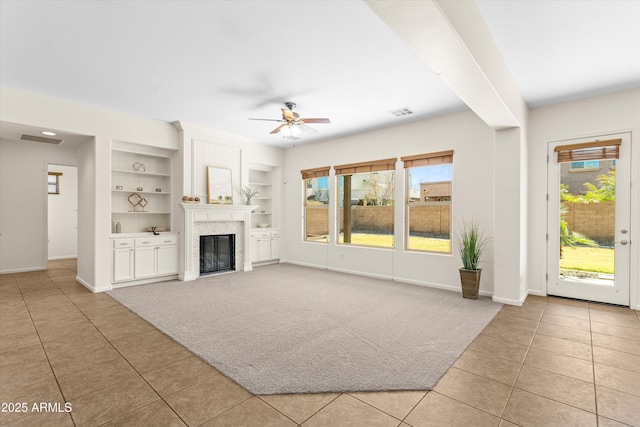 unfurnished living room featuring built in shelves, visible vents, plenty of natural light, and ceiling fan