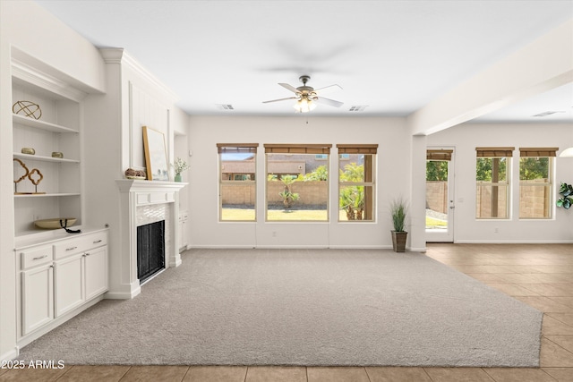 unfurnished living room featuring light carpet, ceiling fan, a fireplace, and visible vents