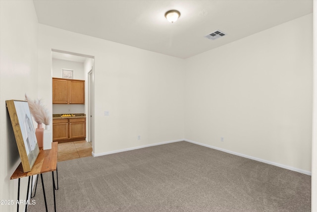 empty room with visible vents, light carpet, and baseboards