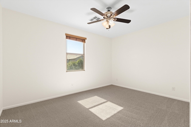 carpeted spare room with visible vents, baseboards, and ceiling fan