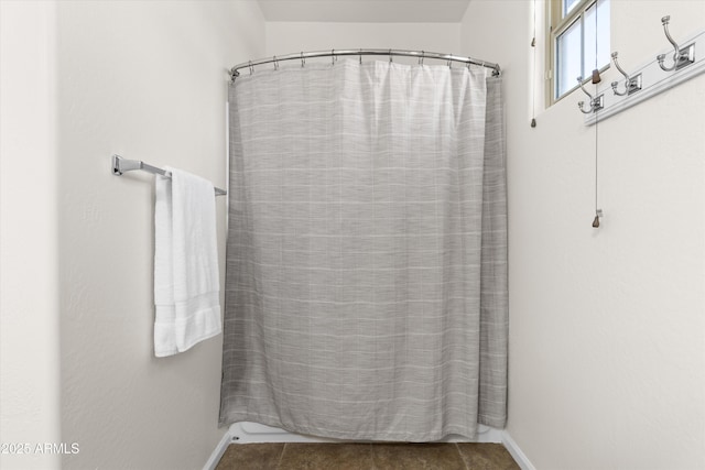 bathroom featuring curtained shower and baseboards