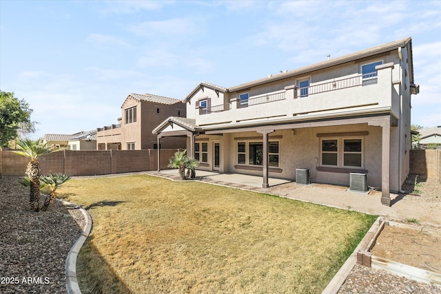 rear view of house with a patio, a fenced backyard, a balcony, a yard, and stucco siding