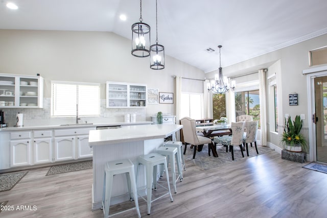 kitchen featuring white cabinets, a notable chandelier, a sink, a kitchen bar, and visible vents