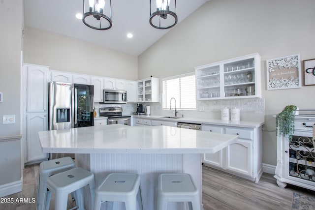 kitchen featuring white cabinets, a breakfast bar, a sink, high vaulted ceiling, and stainless steel appliances