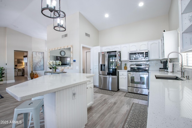 kitchen with visible vents, a sink, appliances with stainless steel finishes, and high vaulted ceiling