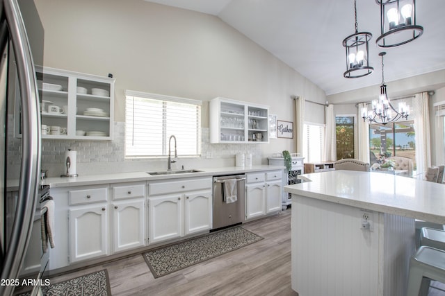 kitchen featuring decorative backsplash, a sink, white cabinets, an inviting chandelier, and stainless steel appliances