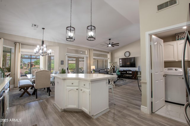 kitchen featuring white cabinets, visible vents, vaulted ceiling, and ceiling fan with notable chandelier