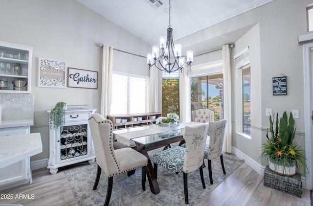 dining room with an inviting chandelier, baseboards, light wood-style floors, and visible vents