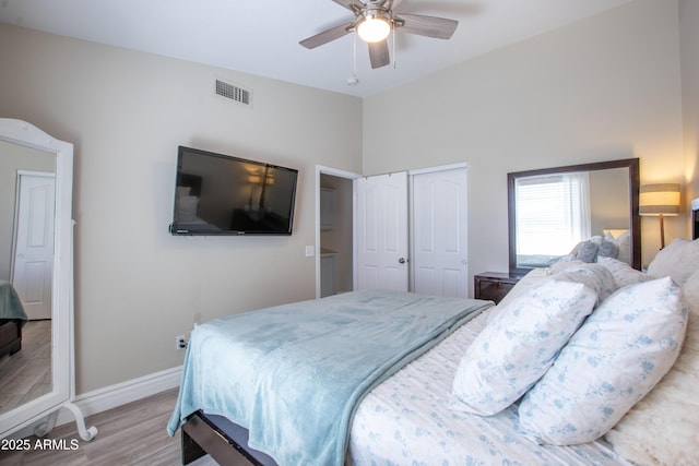 bedroom with ceiling fan, light wood finished floors, baseboards, visible vents, and a closet