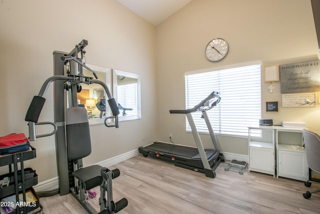 workout area with baseboards, high vaulted ceiling, and light wood-style floors
