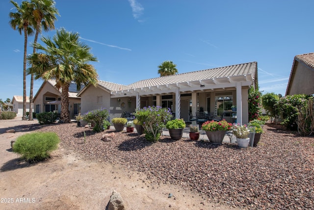 rear view of property featuring a patio, stucco siding, and a tiled roof