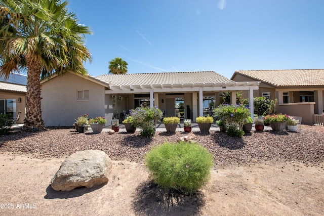 rear view of house featuring a pergola, stucco siding, a patio area, and a tile roof