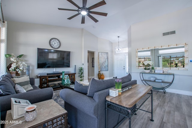 living area featuring visible vents, wood finished floors, baseboards, high vaulted ceiling, and ceiling fan with notable chandelier