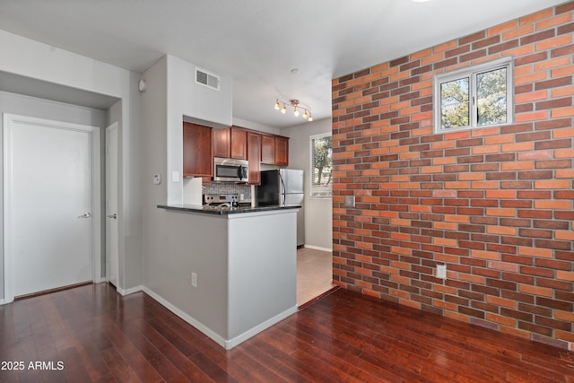 3302 N 7th St Unit 226, Phoenix, AZ 85014 - kitchen with stainless steel appliances, dark countertops, dark wood-style floors, a peninsula, and decorative backsplash