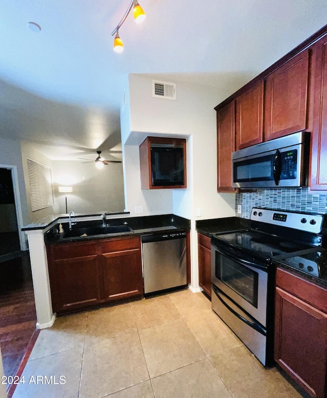 kitchen featuring track lighting, stainless steel appliances, tasteful backsplash, sink, and light tile patterned floors