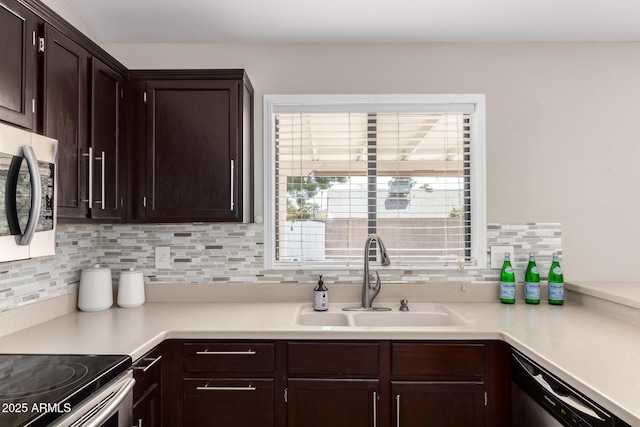 kitchen with stainless steel appliances, light countertops, a sink, and dark brown cabinetry