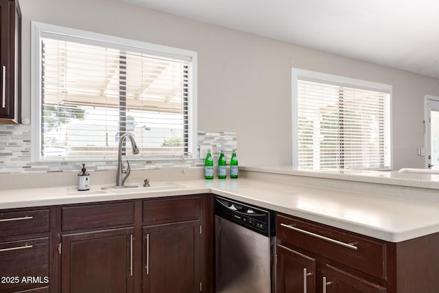 kitchen featuring dishwasher, dark brown cabinets, a sink, and a wealth of natural light