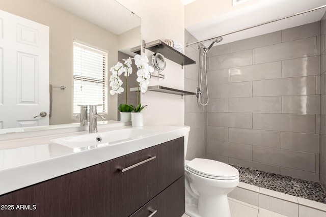 bathroom featuring toilet, tile patterned floors, a tile shower, and vanity