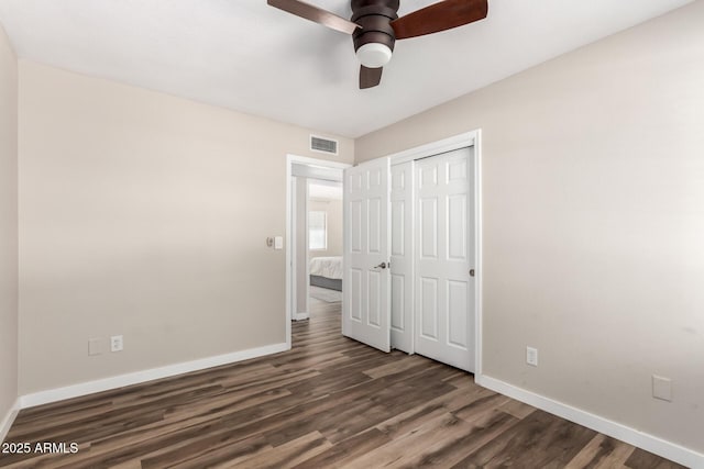 unfurnished bedroom with a closet, wood finished floors, visible vents, and baseboards