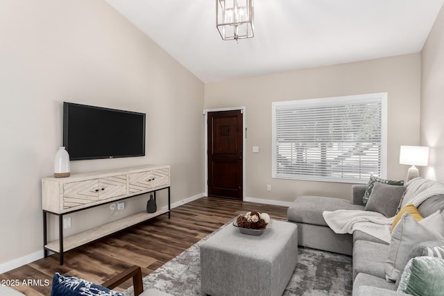 living area with lofted ceiling, baseboards, a chandelier, and wood finished floors