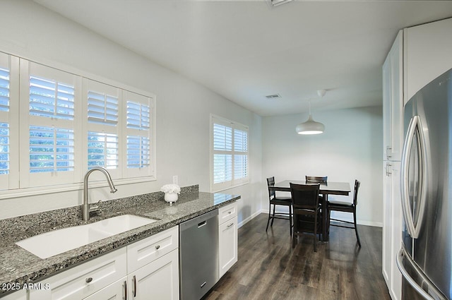 kitchen with pendant lighting, white cabinetry, sink, dark stone countertops, and stainless steel appliances