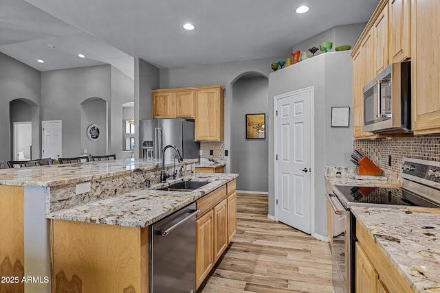 kitchen featuring stainless steel appliances, an island with sink, sink, and decorative backsplash