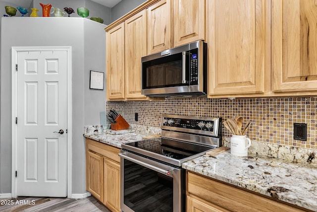 kitchen featuring stainless steel appliances, light brown cabinets, light stone counters, and decorative backsplash