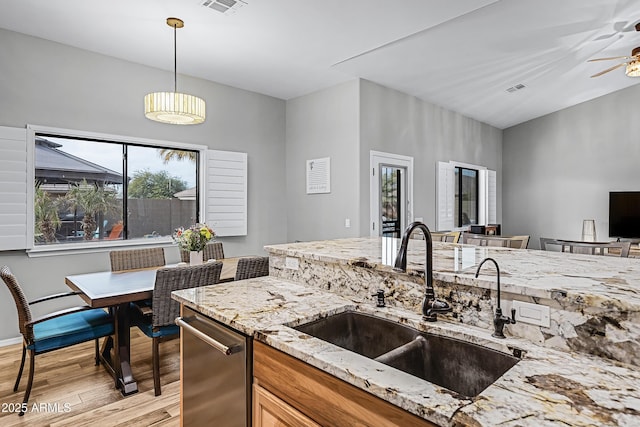 kitchen with sink, light hardwood / wood-style flooring, ceiling fan, hanging light fixtures, and light stone counters