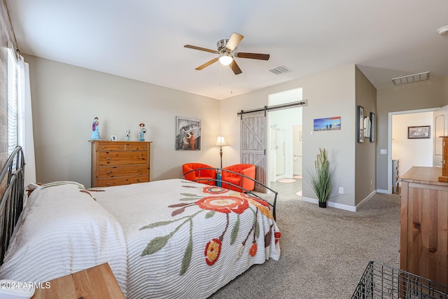 carpeted bedroom featuring a barn door, ceiling fan, and ensuite bath