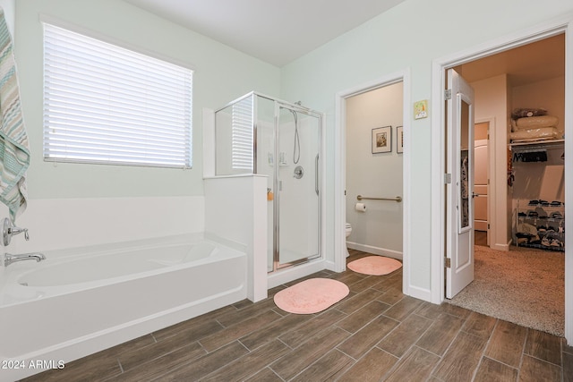 bathroom featuring plus walk in shower, hardwood / wood-style flooring, and toilet