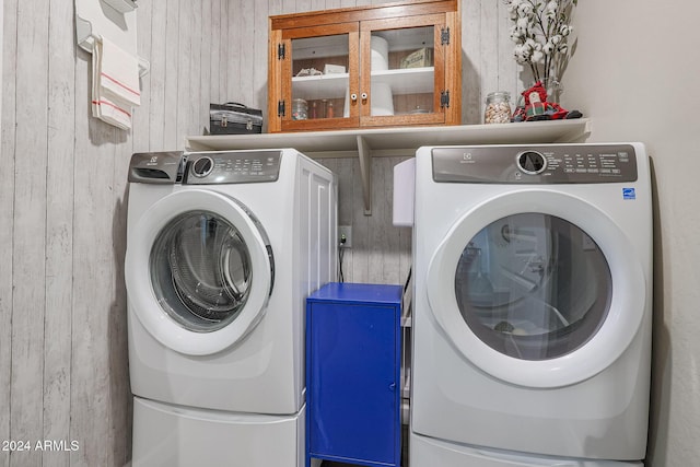 laundry room featuring washing machine and dryer and wooden walls