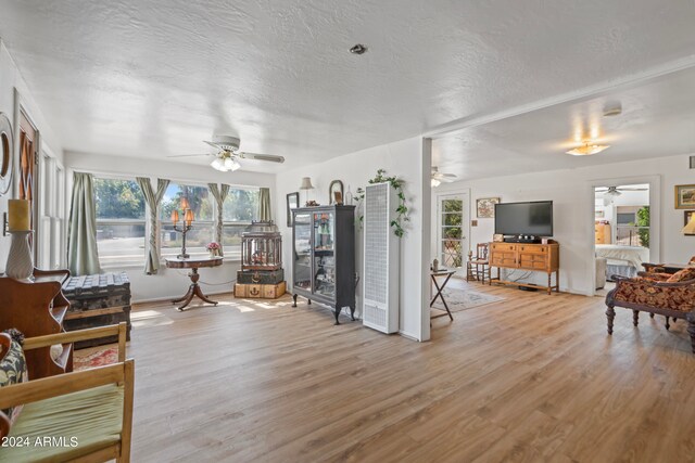 living room featuring wood-type flooring, ceiling fan, and a textured ceiling