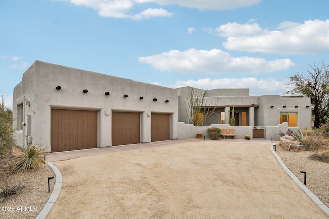 adobe home with driveway, a garage, and stucco siding