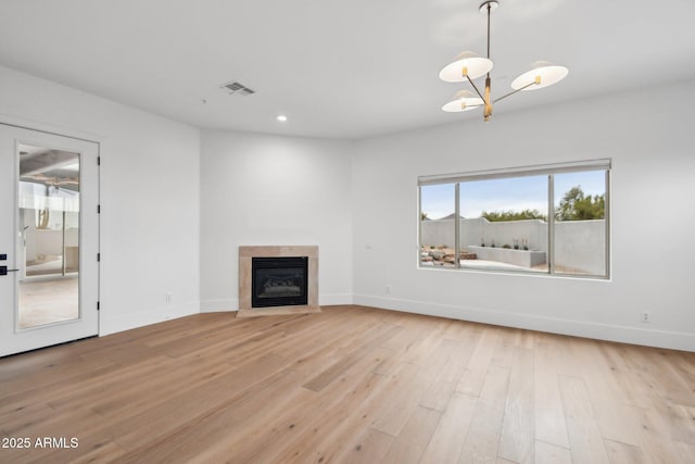 unfurnished living room featuring a fireplace with flush hearth, light wood-type flooring, visible vents, and baseboards