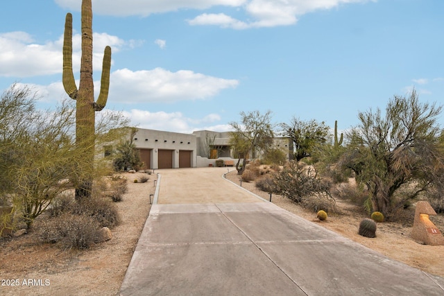 adobe home featuring driveway, an attached garage, and stucco siding