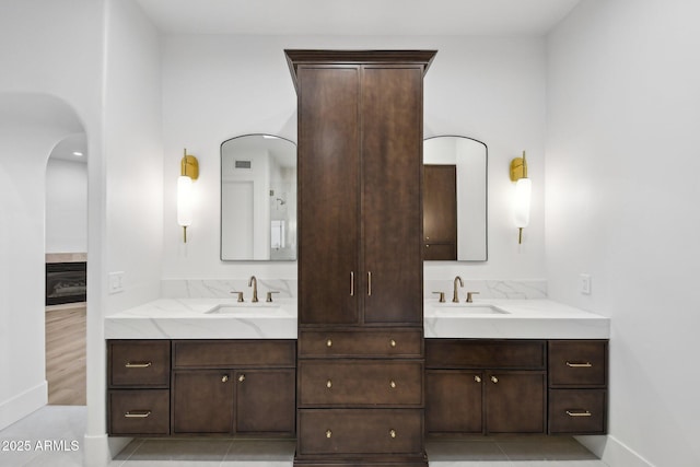 bathroom with a glass covered fireplace, visible vents, vanity, and baseboards