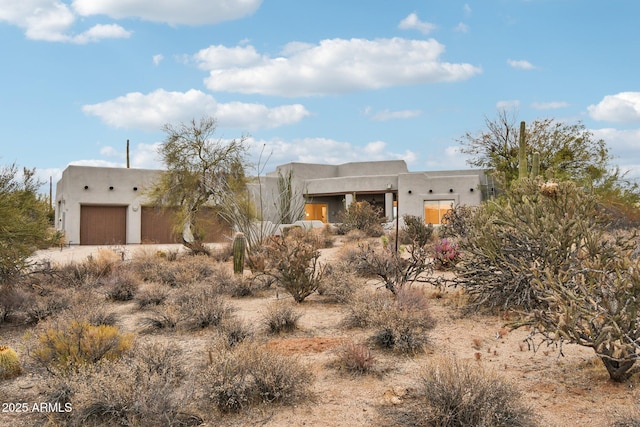 pueblo-style house with a garage and stucco siding