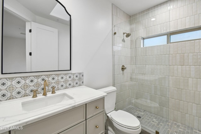 full bathroom featuring tasteful backsplash, a tile shower, vanity, and toilet